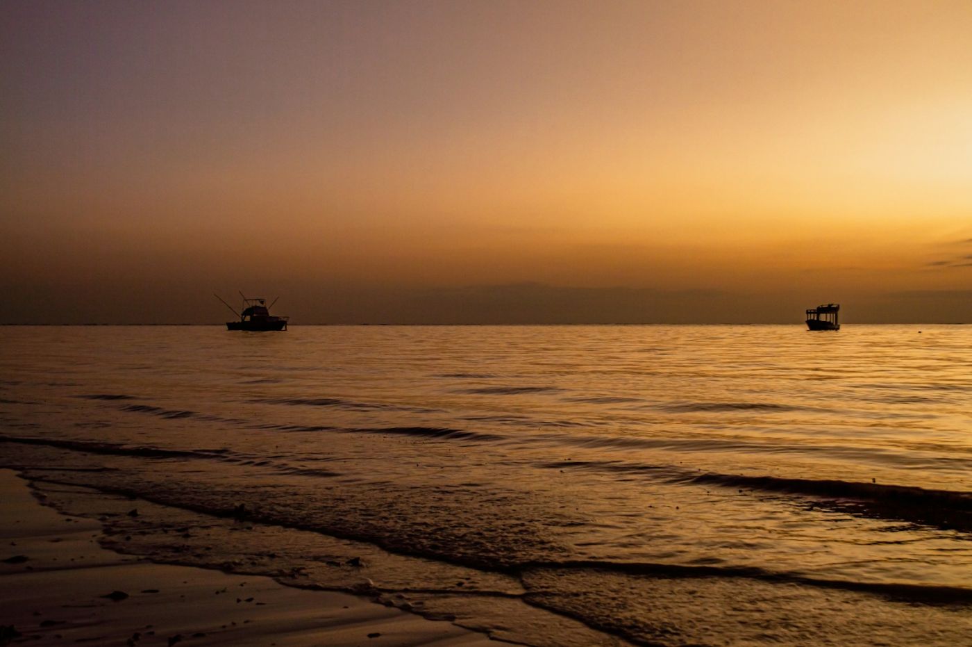 Dhow sailing off a white sand beach at sunset